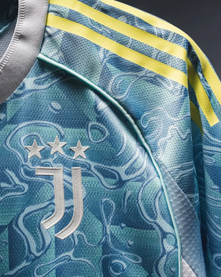Close-up of Juventus away jersey 25-26 with blue camo pattern and yellow stripes from Striker Store