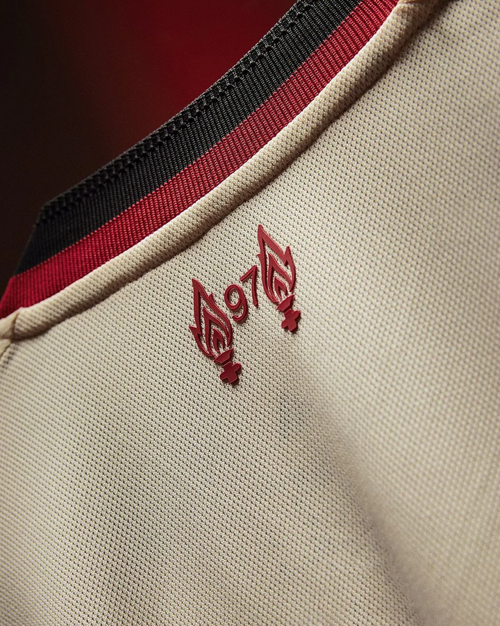 Close up of Striker Store Liverpool Away Jersey 2025-26 beige fabric with red black collar and red 97 flame detail