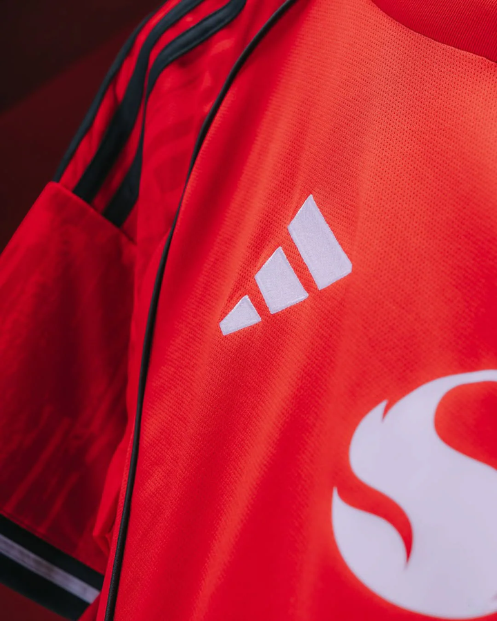 Close-up of Striker Store Manchester United 2025-26 home jersey showing Adidas logo and red fabric details