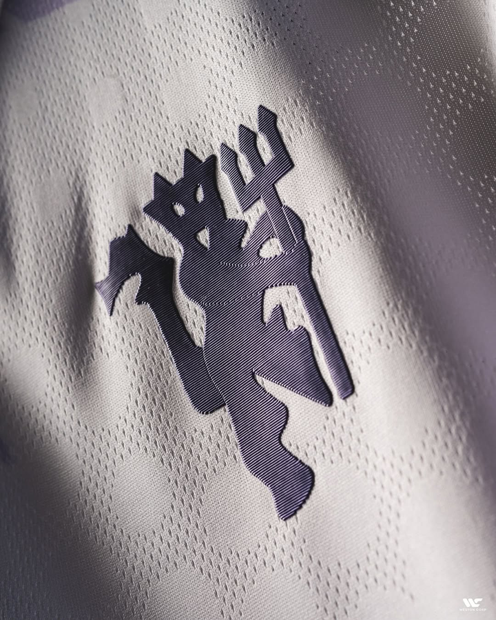 Close-up detail of the Striker Store Manchester United away jersey 2025-26 featuring the club emblem on white fabric