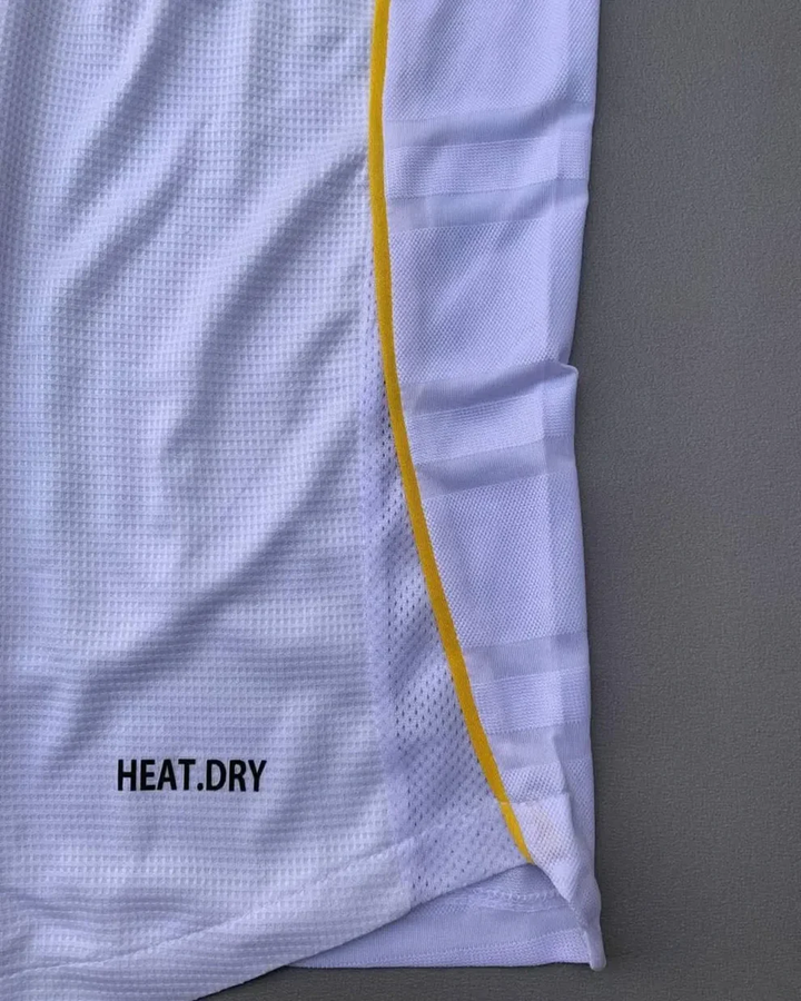 Striker Store close up of Real Madrid 2025 home jersey white mesh with yellow side piping and HEAT DRY branding