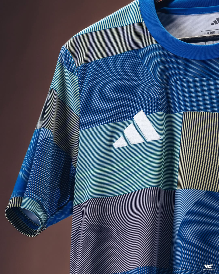 Striker Store Real Madrid pre match jersey 2025 featuring blue multicolor geometric patterns and Adidas logo