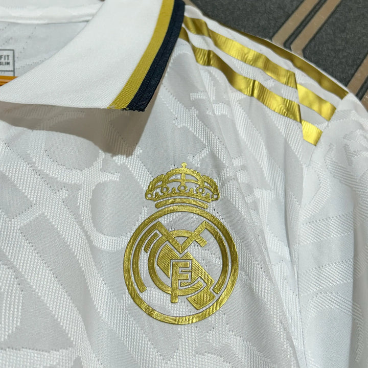 Real Madrid white gold jersey 2024-25 close-up showing gold crest and striped accents on white fabric