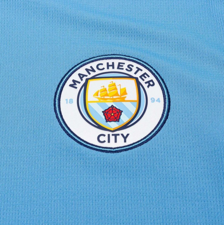 Manchester City home jersey 2024 featuring the iconic club crest in vibrant blue fabric