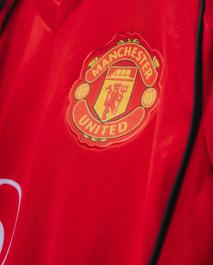 Close-up of Manchester United 2025-26 home jersey red fabric with embroidered club crest