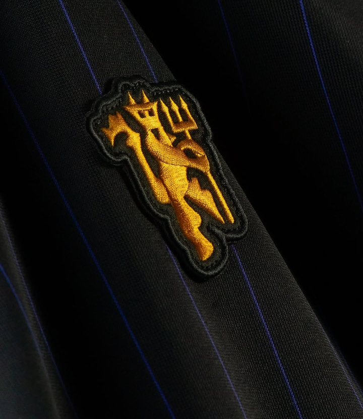 Close-up of the embroidered crest from the Manchester United Terrace Icon jersey 2025-26 featuring a golden design