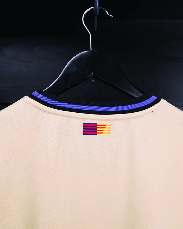 Striker Store Barcelona away jersey 2025-26 beige back view with purple trimmed collar and rear flag detail