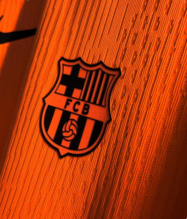 Striker Store close up of orange Barcelona third jersey 2025-26 player version showing embossed club crest and textured fabric