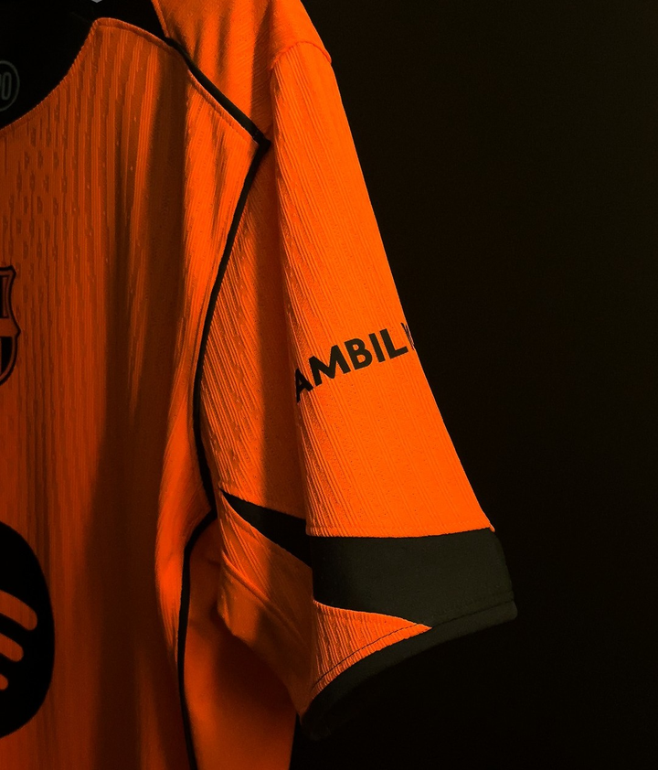 Striker Store close up of orange Barcelona third jersey 2025-26 player version showing sleeve black piping and crest
