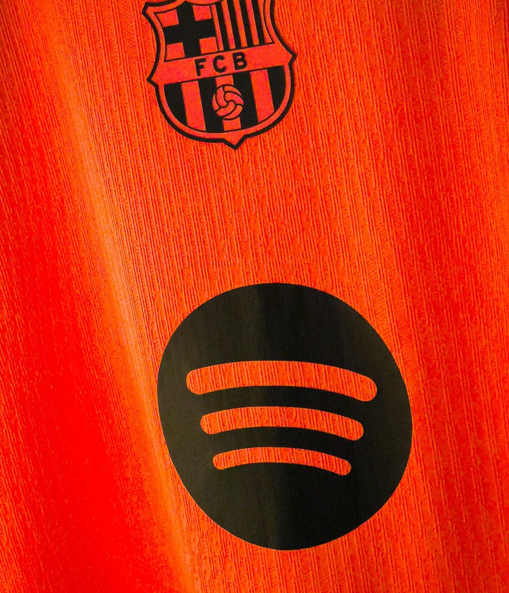 Barcelona third jersey 2025-26 player version close up showing orange kit with FC Barcelona crest and black Spotify logo