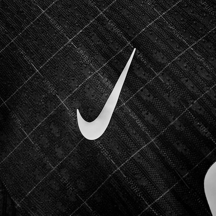Striker Store closeup of Tottenham Hotspur away jersey 2025-26 black fabric with white Nike swoosh and textured check pattern