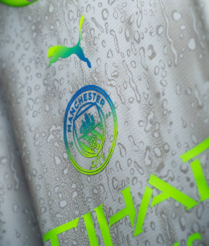 Striker Store close up of Manchester City Third Jersey 2025-26 grey fabric with crest Puma logo and water droplets